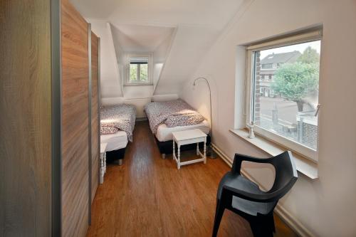 a small room with two beds and a chair at Vakantieappartement Diepstraat in Eijsden