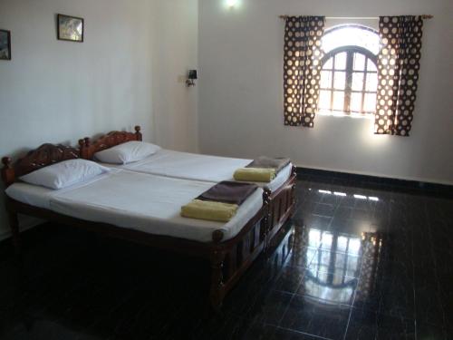 a bedroom with a bed with white sheets and a window at Leon Hide Out Guest House in Vasco Da Gama