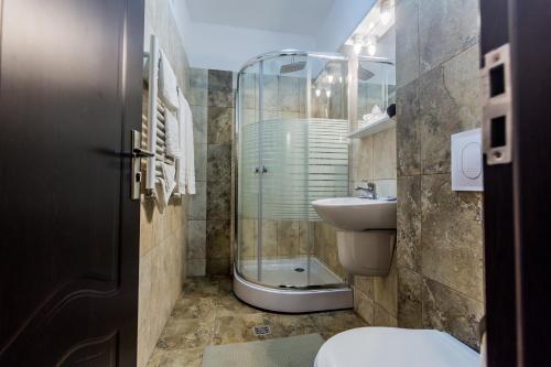 a bathroom with a toilet and a glass shower at Pensiunea Raxand in Mioveni