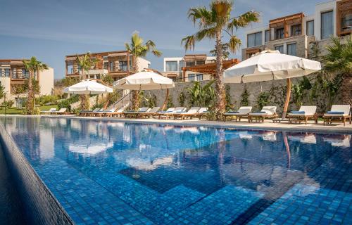 a large swimming pool with umbrellas and lounge chairs at Allium Bodrum Resort & Spa in Yalıkavak