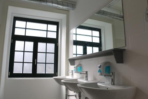 a bathroom with a row of sinks and a mirror at Nice Way Porto Hostel in Porto