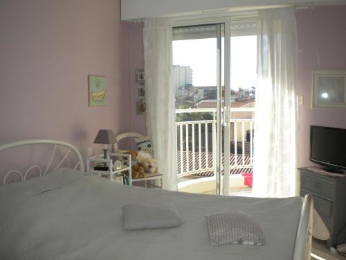 レ・サ​​ーブル・ドロンヌにあるRésidence Le Regentのベッドルーム1室(ベッド1台付)、窓、バルコニーが備わります。