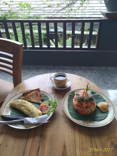 a wooden table with two plates of food on it at Praety Home Stay in Ubud