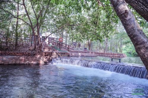 a waterfall in the middle of a river with trees at Prime Hotel Águas da Serra in Rio Quente