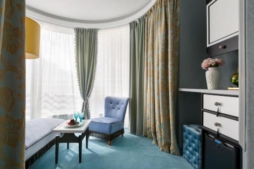 1 dormitorio con 1 cama, 1 silla y 1 ventana en Statskij Sovetnik Hotel Zagorodnyy, en San Petersburgo