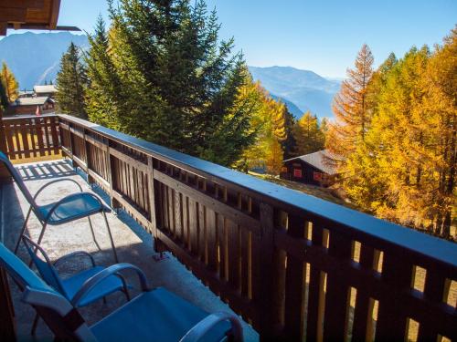 a balcony with two chairs and a view of the mountains at Chalet Bärgsunna in Rosswald