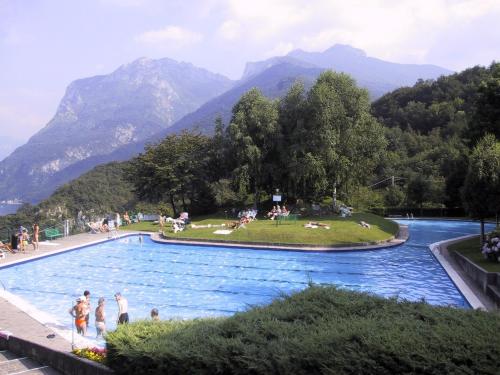 a group of people in a swimming pool with mountains in the background at Appartamenti Lago di Como in Valbrona