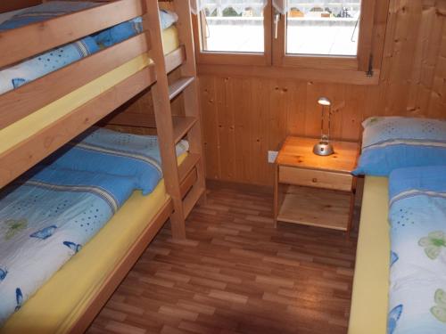 two bunk beds in a room with a table at Chalet Skilift in Rosswald