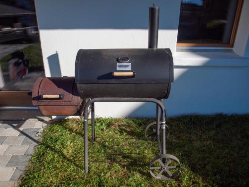 a barbecue grill sitting in the grass next to a building at Chalet Bergfink in Rosswald