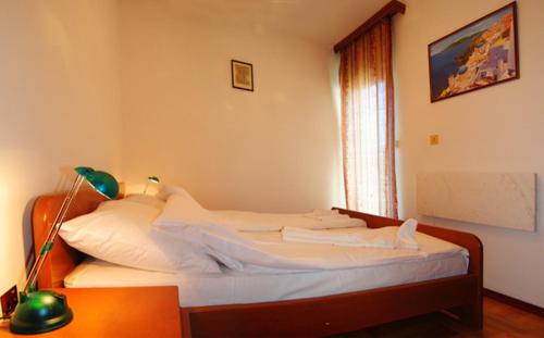 1 dormitorio con 1 cama con sábanas blancas y lámpara en Apartman Lili, en Vrnjačka Banja