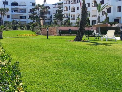 a park with green grass and buildings in the background at Marina Beach Appartements in Restinga Smir
