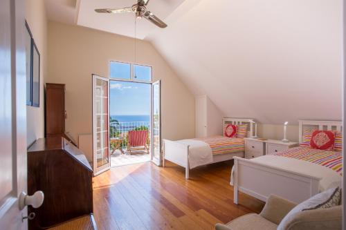 フンシャルにあるCasa dos Francelhosのベッドルーム1室(ベッド2台付)、海を望むバルコニーが備わります。