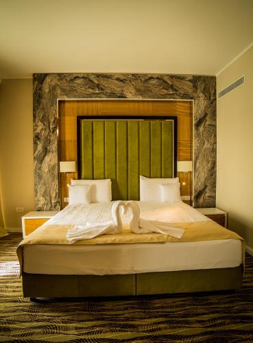 a bedroom with a large bed with a large headboard at Hotel President SPA in Baile Felix
