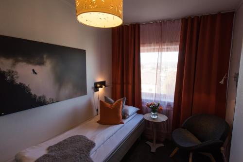 a room with a bed with a window and a chair at Breidablikk Guesthouse in Narvik