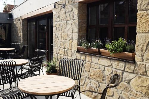 a patio with tables and chairs and a stone wall at PROSECCO RESIDENCE MARKO in Valtice