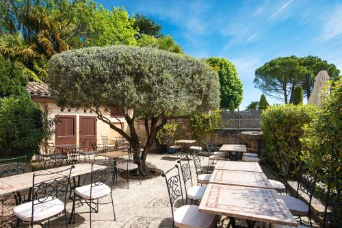 a patio with tables and chairs and a tree at Hôtel Au Logis des Remparts in Saint-Émilion
