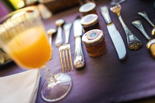 a table with a glass of orange juice and silverware at Hôtel Au Logis des Remparts in Saint-Émilion