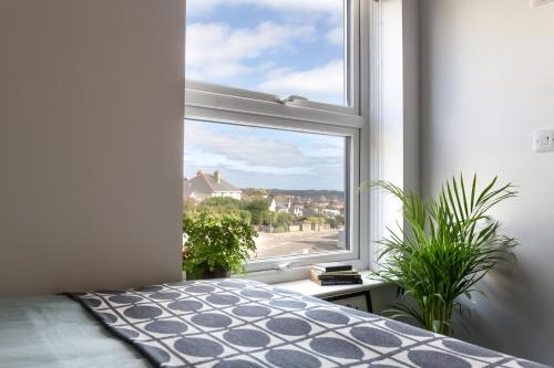 a bedroom with a window with a bed and plants at Roseland House in Falmouth
