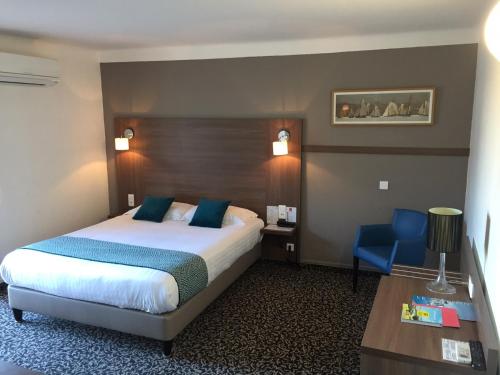 a hotel room with a bed and a blue chair at Le Galion Hotel et Restaurant Canet Plage - Logis in Canet-en-Roussillon