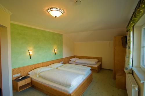 two beds in a room with green walls at Pension Oberhorner in Schladming