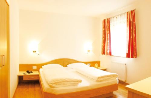 a bedroom with a bed with white sheets and a window at Hotel Sonnenhof in Marlengo