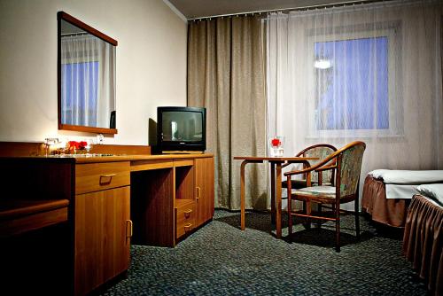 a hotel room with a desk with a television and a bed at Krechowiak in Augustów