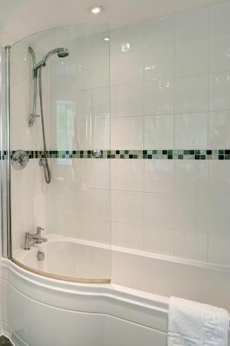 a bathroom with a tub and a glass shower at Lord Haldon Country Hotel, Sure Hotel Collection by Best Western in Exeter