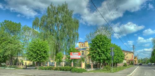 a building on the corner of a street with trees at Nashe Misto Guest House in Kovelʼ