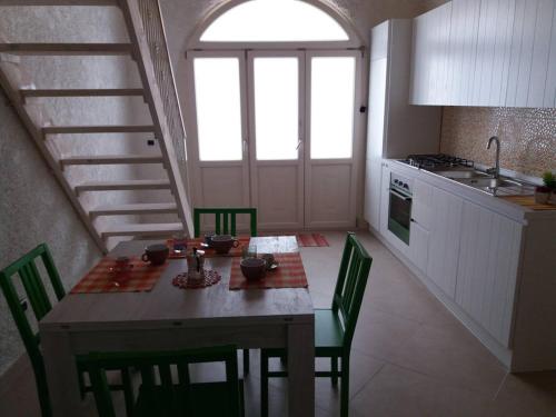 メレンドゥーニョにあるAppartamento Corte Incasili "B"のキッチン(テーブル、緑の椅子、階段付)