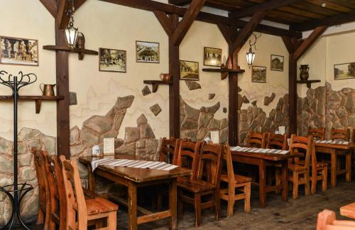 a restaurant with wooden tables and chairs and a mural at Nashe Misto Guest House in Kovel