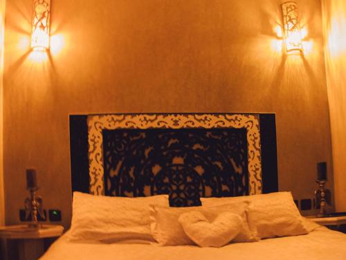 a bedroom with a bed with two lights on the wall at Riad Golf Stinia 1 in Meknès