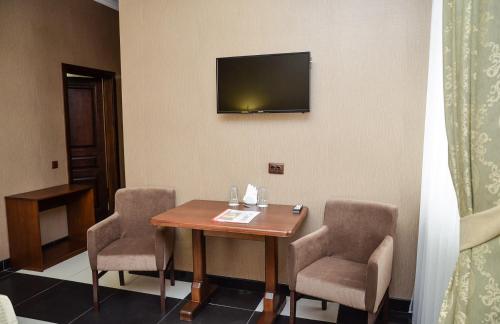 a room with a table and two chairs and a television at Nashe Misto Guest House in Kovelʼ