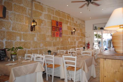 un restaurant avec des tables et des chaises blanches et un mur en briques dans l'établissement Hôtel Restaurant Le Provençal, au Grau-du-Roi