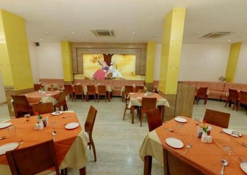 a dining room with tables and chairs and a painting at Parijatha Gateway in Bengaluru