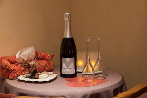 a bottle of wine and two glasses on a table at Domaine et chambres d'Hôtes des Fées in Pretin
