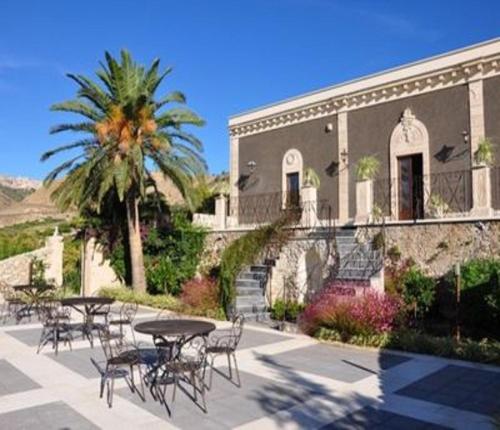 um edifício com mesas e cadeiras e uma palmeira em Vecchia Dimora Resort em Centuripe