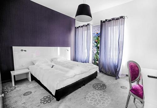a bedroom with a large bed and a purple wall at Lawendowe Termy in Uniejow