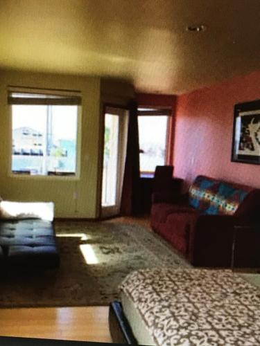 een slaapkamer met een bed, een bank en ramen bij Apocalypto Motel in Neah Bay