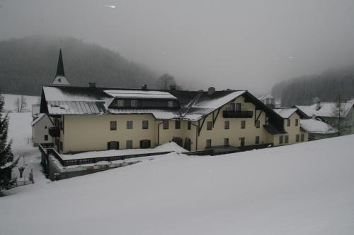 a large building in the snow with snow covered roofs at Gasthof Kirchenwirt in Lackenhof
