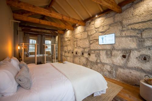 Un dormitorio con una cama en una pared de piedra. en Laurear Guest House, en Oporto