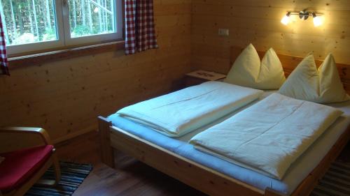 una camera da letto con un letto con lenzuola e cuscini bianchi di Ferienhäuser Stohl a Mariapfarr