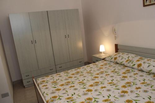 トッレ・スーダにあるCase Vacanza Rossellaのベッドルーム1室(花柄のベッドカバー、キャビネット付)