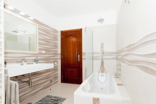 Un baño con bañera, lavabo y espejo. en Villa Tara, Heated private pool, short walk to to town & beach, en Carvoeiro