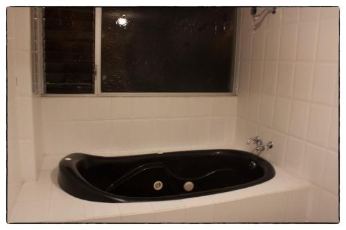 una bañera negra sentada bajo una ventana en un baño en Sueños del Valle en Sangolquí
