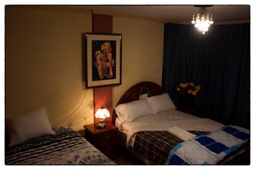 Sueños del Valle في Sangolquí: غرفة نوم بسريرين وصورة على الحائط