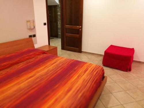 um quarto com uma cama com um cobertor colorido e um banco vermelho em Appartamento Rosa em Aosta
