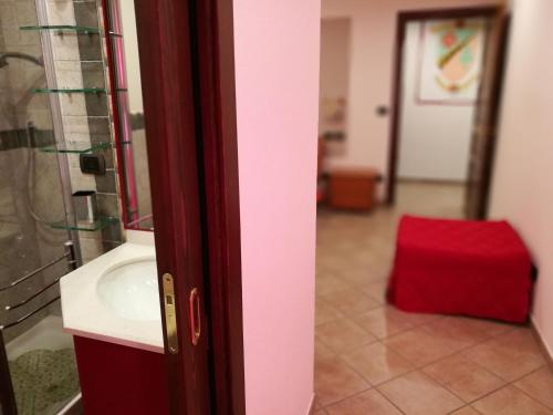 uma casa de banho com um lavatório e uma mala vermelha em Appartamento Rosa em Aosta