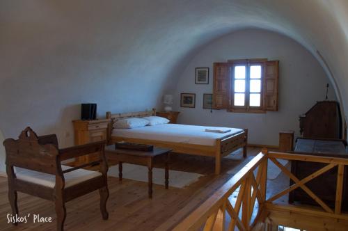a bedroom with a bed and a chair and a window at Siskosplace in Oia