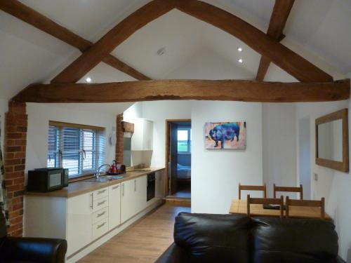 a living room with a couch and a kitchen at White House Farm Cottages in West Haddon