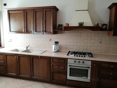 uma cozinha com armários de madeira e um fogão e lavatório em Appartamento Rosa em Aosta